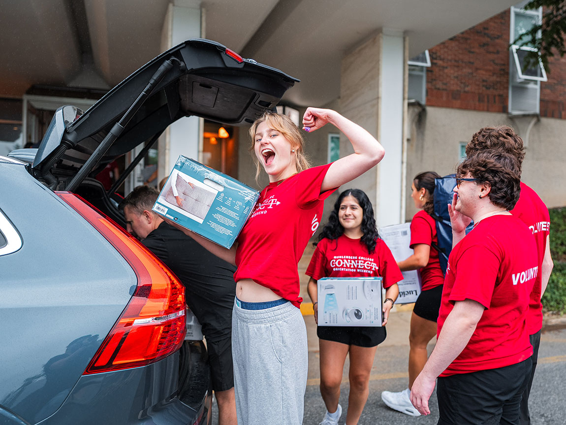 A college student flexes while helping with move-in